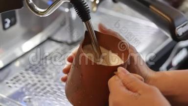 专业咖啡师。 制作新鲜的磨碎咖啡，咖啡师制作拿铁艺术，在制作过程中将牛奶倒入杯子
